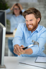 angry businessman swinging hammer towards his computer