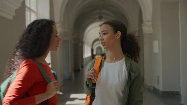 Sad upset frustrated stressed Hispanic Latina woman girl student walking going in corridor of college university high school Caucasian female friend support calming talking friendship two women girls