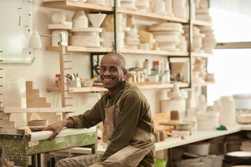 Smiling African potter sitting at a bench in a pottery workshop