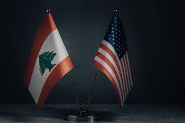 Table flags United States America and National Flag Lebanon on dark background,political concept.