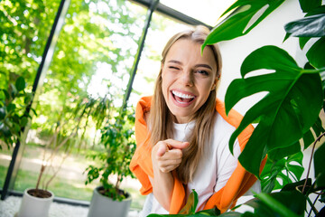 Photo of positive good mood woman dressed white t-shirt smiling winking pointing finger you indoors...