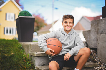 Young child boy with basketball outside of his home