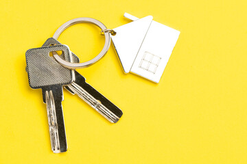 House keys with house shaped keychain on yellow background. Real estate concept.