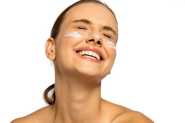 Beautiful young happy woman posing with a cosmetic product on her face