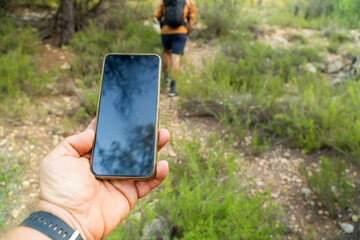  Male hand of a hiker, holding a smartphone, blank screen.