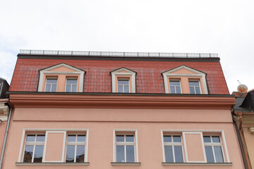 There is a charming building that features a bright red roof along with numerous windows that...