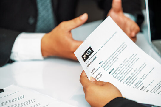 Human resources department manager reads CV resume document of an employee candidate at interview room. Job application, recruit and labor hiring concept. uds