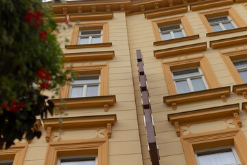A tall building featuring an abundance of large windows, complemented by a beautiful tree situated...