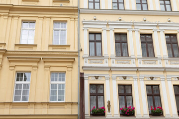 There are two charming buildings situated closely side by side, each adorned with beautiful flowers blooming in their windows