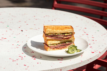 Portion of gourmet sandwich with pickles on the cafe table