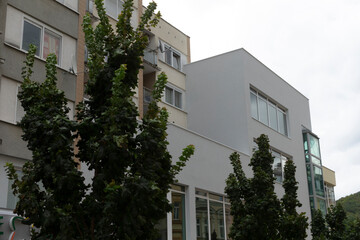 There is a large building that features a significant number of windows, and in front of it, several trees can be seen growing