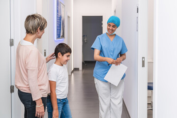 Fototapeta premium Dental hygienist leading mother and child into the treatment room for dental care