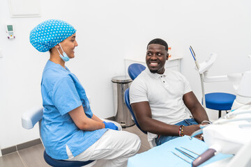 Obraz premium Dental hygienist and African male patient having a pleasant conversation before dental treatment.