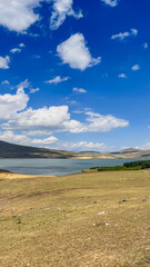 A serene landscape of a tranquil lake surrounded by rolling hills under a clear blue sky, ideal for nature exploration