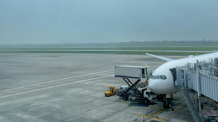 A large commercial airplane is parked at an airport gate, illustrating travel and holiday preparations amidst gray skies