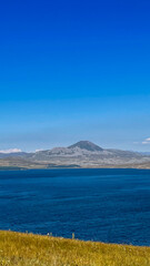 A serene mountain landscape with a clear blue sky and calm waters, perfect for promoting relaxation and tranquility