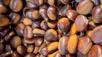 A close-up of shiny brown chestnuts, ideal for autumn, harvest season, and holiday cooking themes like Thanksgiving
