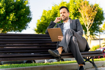 Middle aged businessman on a phone call from the park with headphones