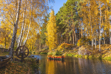 Wooden boat floating on water in autumn forest park