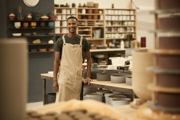 Smiling young African potter working in a large ceramics workshop