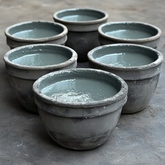 Fototapeta premium Handcrafted gray ceramic pots filled with water in a serene artisan workshop setting