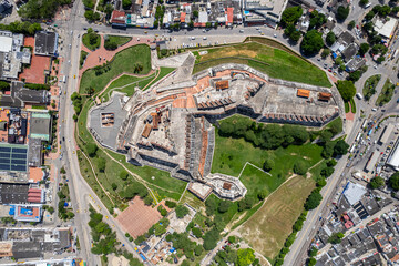 Fototapeta premium Beautiful aerial drone view of the San Felipe Castle, with the huge Cartagena Flag waving and the city in the the background