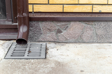 Drainage system in concrete blind area. Downpipe and drain grate. The basement of the house is...