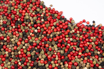 A mixture of different peppercorns on a white background, top view