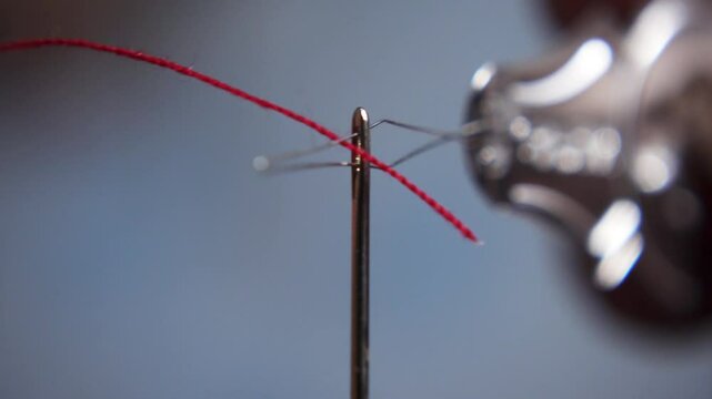 Macro shot of needle threader. Use needle threader. Needle with red thread close-up