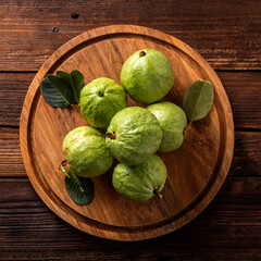guava fruit on a wooden cutting board, isolated against a wooden background