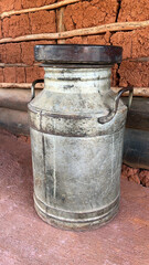 Old iron container for transporting fresh milk on a rustic background.