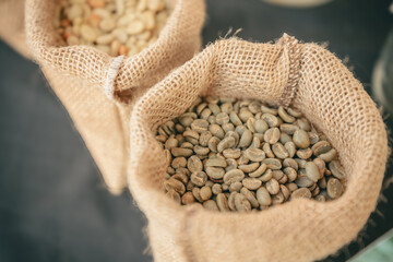 Close-up of burlap sacks filled with raw green coffee beans, ready for roasting. Natural texture...