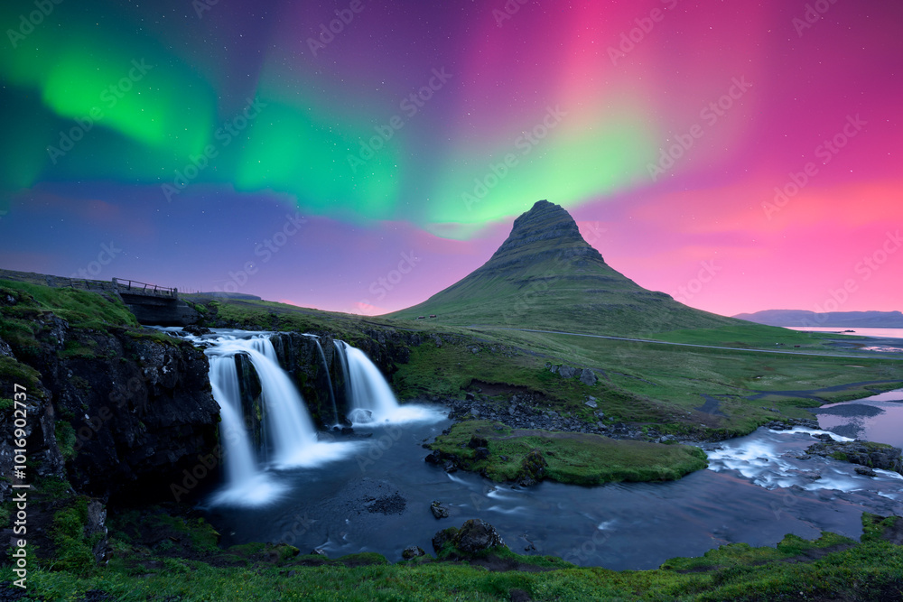 Wall mural Incredible icelandic landscape with Kirkjufellsfoss waterfall under incredible sky with Northern lights. Kirkjufell volkano mountain and Polar lights in Iceland. Aurora borealis