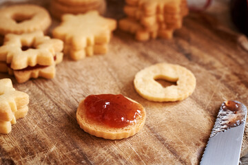 Christmas baking - filling circle shaped Linzer Christmas cookies with strawberry marmalade, close up