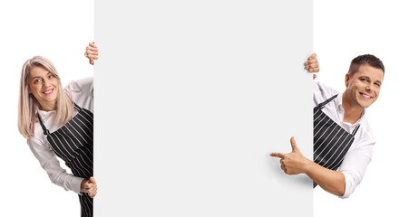 Young male and female baristas behind a blank panel