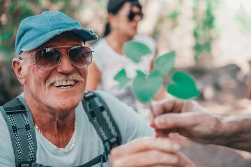 Portrait of old smiling caucasian senior man in outdoors excursion offering a small brunch to a lady