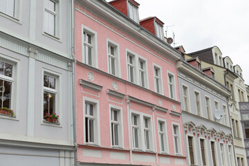 There is a long row of buildings, and prominently situated in the middle of this row is a striking pink building
