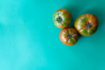 three red tomatoes on green background