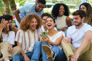 Group of young adults are having fun using a smartphone in a park