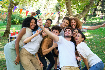 Happy multiracial friends taking a selfie together at a birthday party in the park