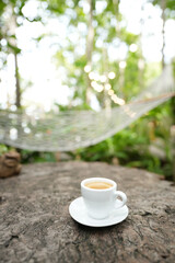 White coffee cup with hammock in the background outdoor relaxing