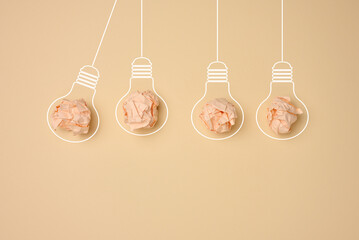 Crumpled balls of paper inside an electric lamp on a beige background. Concept of new ideas,...