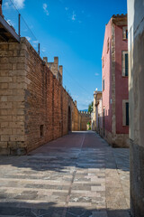 Alcudia, Mallorca, city street in the old town with castle wall, clear sky, vertical shot, majorca
