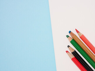 Fototapeta premium Multicolored wooden pencils on a blue background, top view