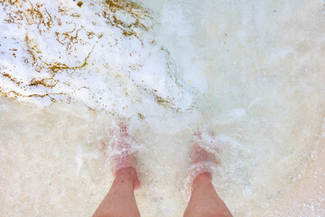 Fototapeta premium A person's feet are in the water, and the water is white