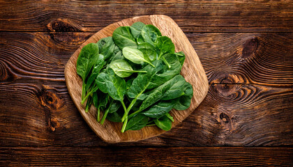 Fototapeta premium spinach on a wooden cutting board, isolated against a wooden background