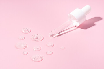 A dropper bottle pipette on a transparent serum smears, swatches, drops on a pink background