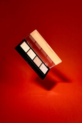 A palette of eyeshadows on a red background. Perfect for beauty, fashion,