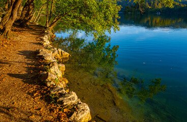Idyllic panorama of spring summer nature. The tranquil transparent waters of lake in the background. Beautiful nature lake. Landscape Reflection in clear lake water surface. Calm river in the forest.