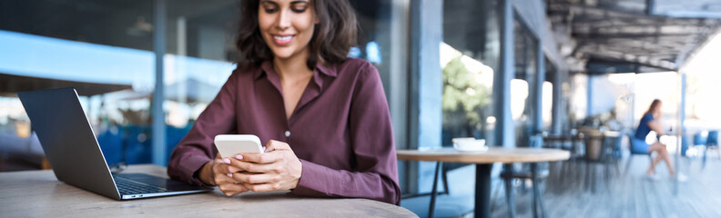 Fototapeta premium Impersonal closeup business woman entrepreneur hands using cell phone mobile app. Young female student holding smartphone for shopping, online browsing, learning, sitting at cafe. Banner, copy space
